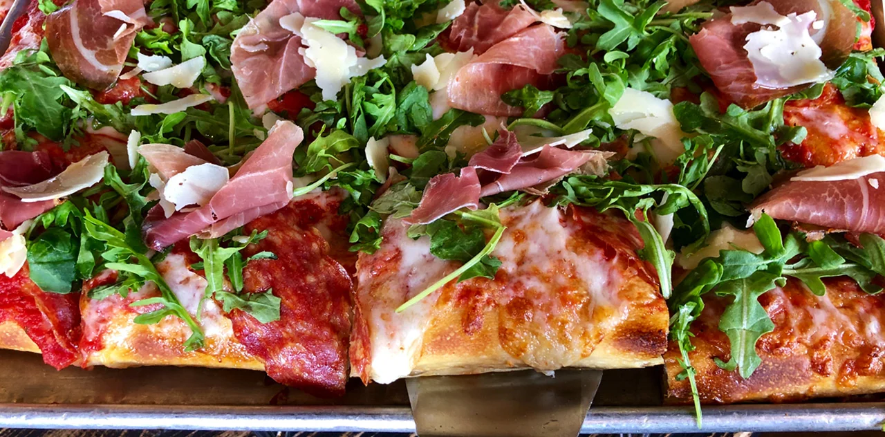Pizza topped with greens and cured meat at Pizza Rock