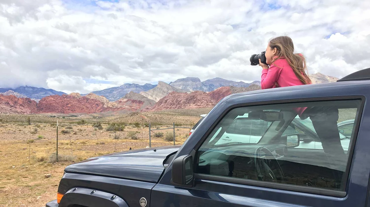 A visitor beside a vehicle overlooking Red Rock Canyon